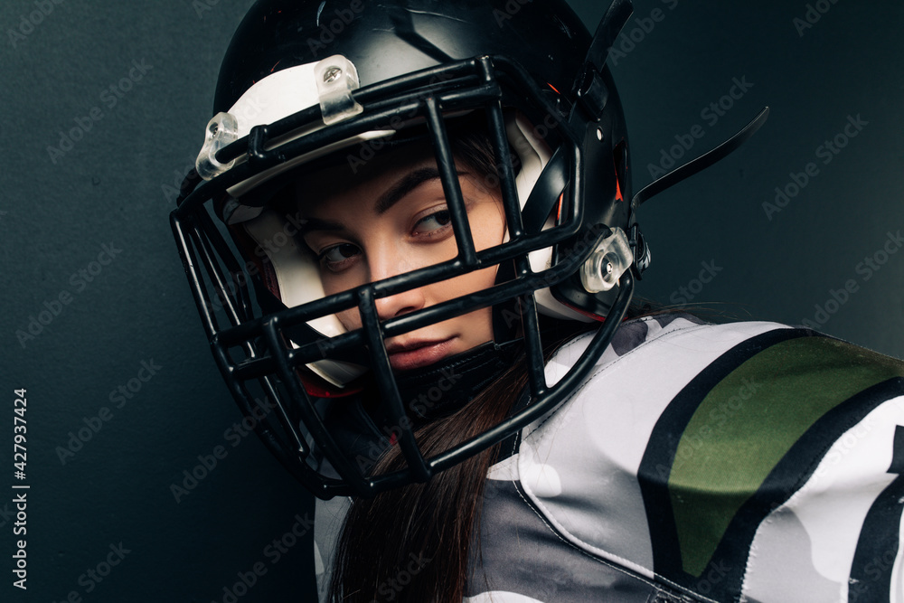 Portrait of young woman in American football uniform and helmet.