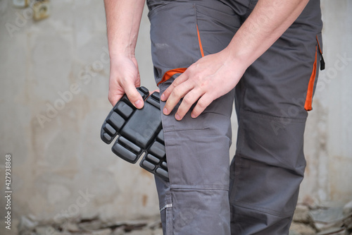 Billede på lærred Unrecognizable builder wearing knee protection pads to work in a construction