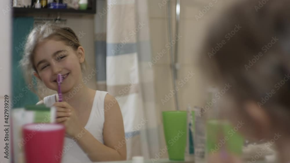 Close-up Portrait Young Little Girl Dancing Singing With Toothbrush in Bathroom Looking at Mirror Reflection. Daily Routine Dental Hygiene. Happy Portrait Caucasian Toothless Child Dancing in Bathroom Close-up Portrait Young Little Girl Dancing Singing With Toothbrush in Bathroom Looking at Mirror Reflection. Daily Routine Dental Hygiene. Happy Portrait Caucasian Toothless Child Dancing in Bathroom