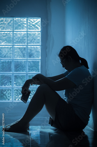 Silhouette depress woman sitting and hold smartphone in hand. photo