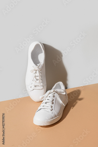 Obraz na płótnie White women's new gumshoes on grey and beige background. Washing and cleaning concept. Vertical format. Close up. w salonie