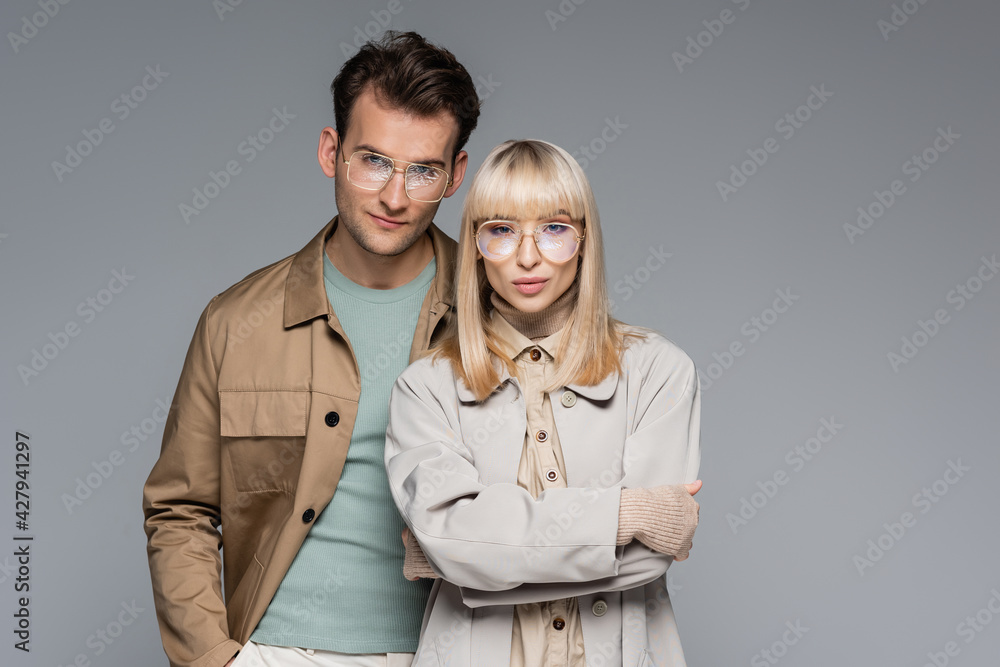stylish couple in glasses posing and looking at camera isolated on grey stylish couple in glasses posing and looking at camera isolated on grey