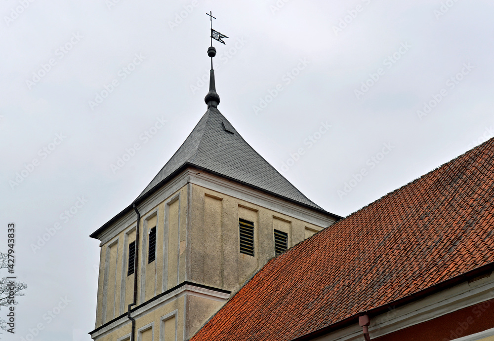 Close-up photos of the side door of the temple and the tower serving as the belfry in the Catholic Church of Our Lady of Rosary in Szarejki in Masuria, Poland. Close-up photos of the side door of the temple and the tower serving as the belfry in the Catholic Church of Our Lady of Rosary in Szarejki in Masuria, Poland.