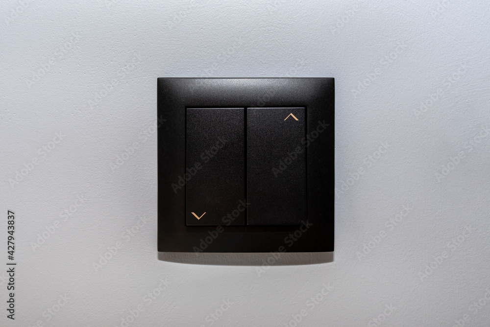 Black frame and button of the roller shutter switch up and down on gray wall in the house. Black frame and button of the roller shutter switch up and down on gray wall in the house.