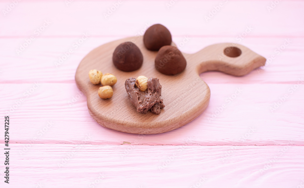 Рand made chocolate truffles dusted with cocoa powder on a wooden board. Рand made chocolate truffles dusted with cocoa powder on a wooden board.