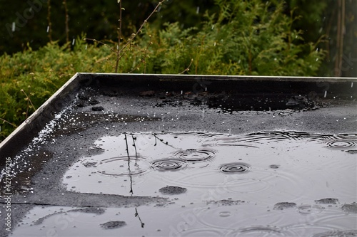 Light rain on a black flat roof against a green background