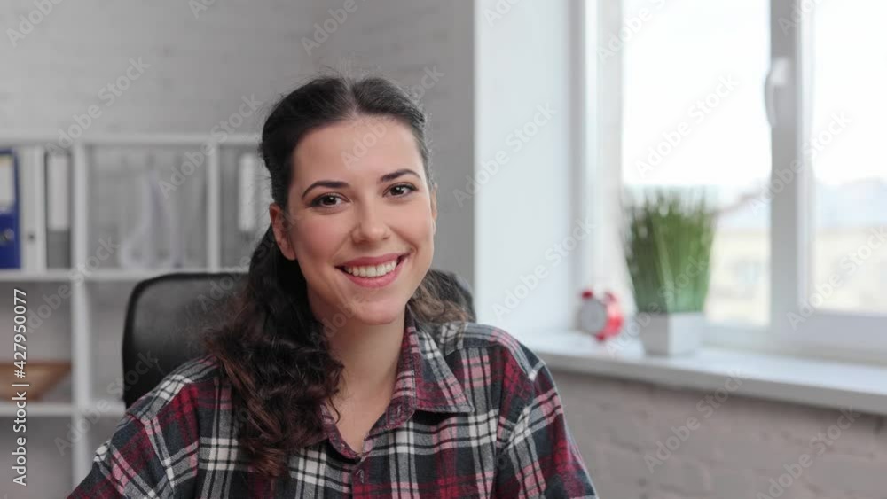 Attractive curly woman look at the camera. work from home. Office worker. Close up young woman portrait. Beautiful brunette female look at the camera and smiling joyfully in the office room. Indoor. Attractive curly woman look at the camera. work from home. Office worker. Close up young woman portrait. Beautiful brunette female look at the camera and smiling joyfully in the office room. Indoor.