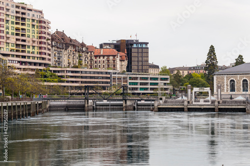 Horizontal soft daylight view of the river Rhone with a footbridge across and buildings in the background, Geneva, Switzerland