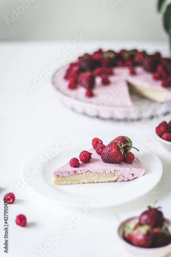 Cheesecake with strawberries on plate, white table background
