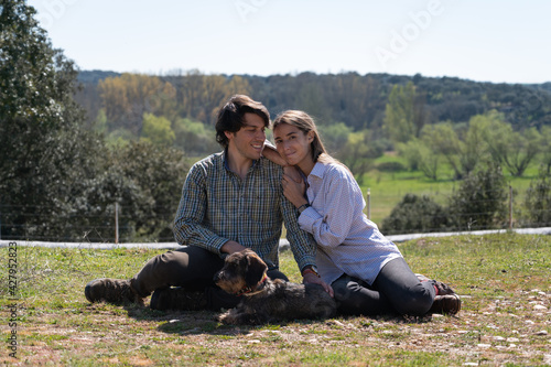 young couple enjoying their puppy in the nature