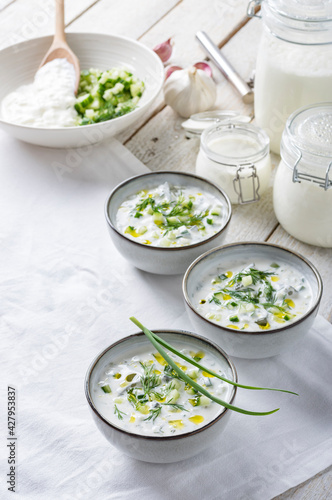 Traditional summer cold soup of homemade yogurt, cucumbers and fresh herbs on a table