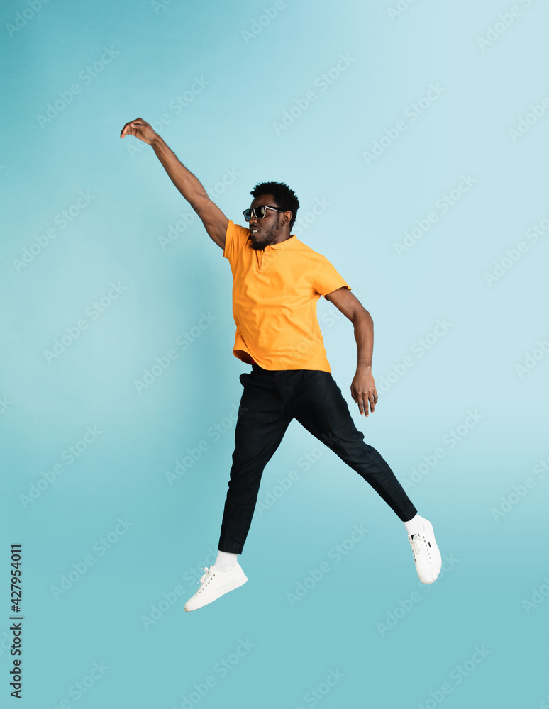 Full length portrait of African young man isolated over blue studio background with copyspace