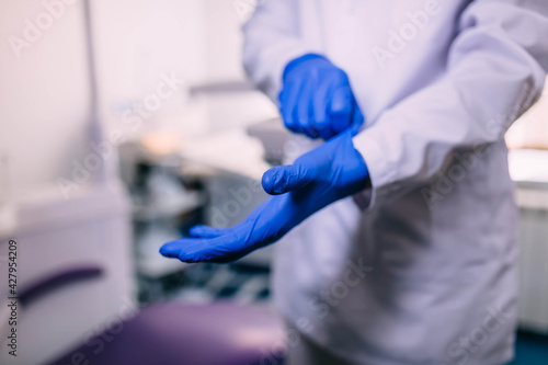 Hands put on blue medical gloves. Means of protecting medical workers from viruses.