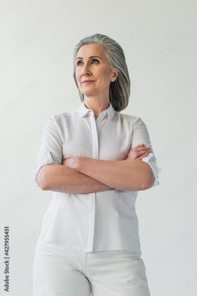 Middle aged woman looking away while standing isolated on grey Middle aged woman looking away while standing isolated on grey