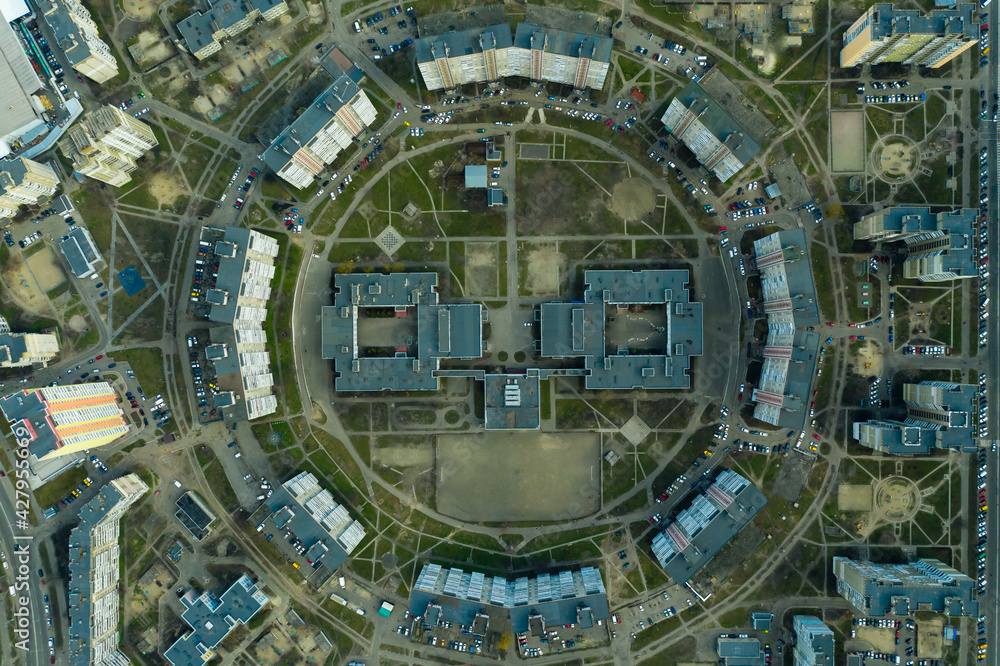 city planning from the sky. the circular architecture of residential buildings surrounds a school with a swimming pool and a football stadium. funny architecture looks like a smile. 4k Aerial