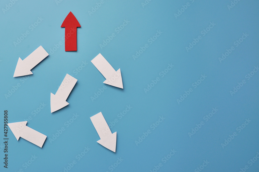 There are many white arrows pointing in different directions and one red arrow pointing up. A symbol of an innovative, different way in life and business There are many white arrows pointing in different directions and one red arrow pointing up. A symbol of an innovative, different way in life and business