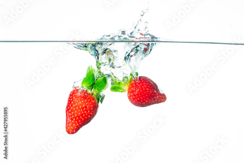 Strawberry falling in water. Splashing water