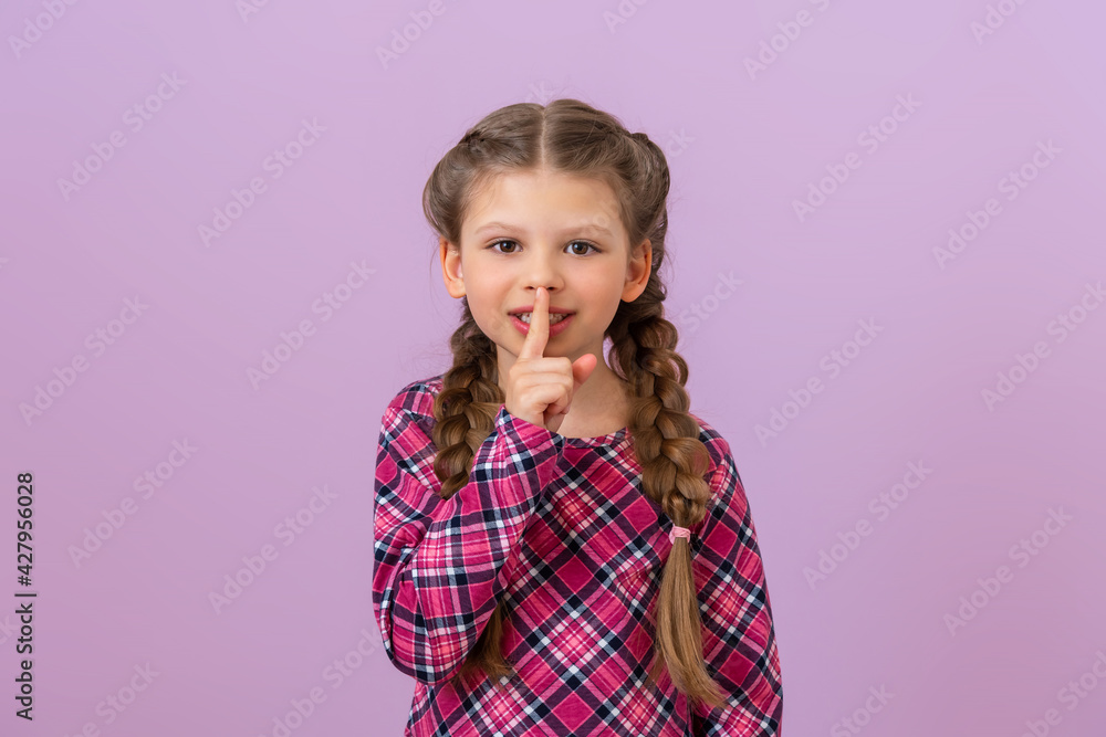 A little beautiful girl holds her finger near her lips. Please be quiet. A little beautiful girl holds her finger near her lips. Please be quiet.
