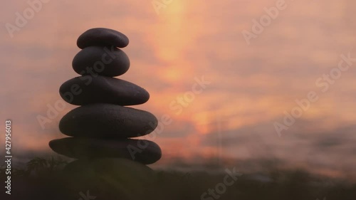 A hand lays a stone on top of a tower of stones. Harmony and balance concept