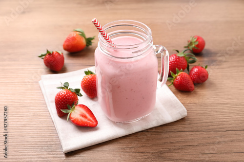 Delicious strawberry drink in mason jar on wooden table