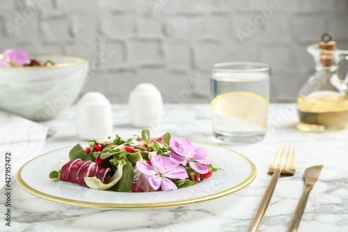 Fresh spring salad with flowers served on white marble table