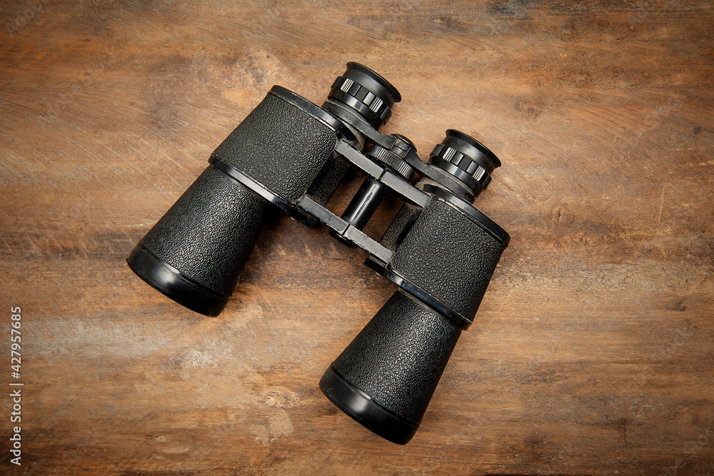 Old sea binoculars isolated on the wooden background Old sea binoculars isolated on the wooden background