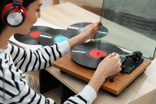 Woman listening to music with turntable at home photo