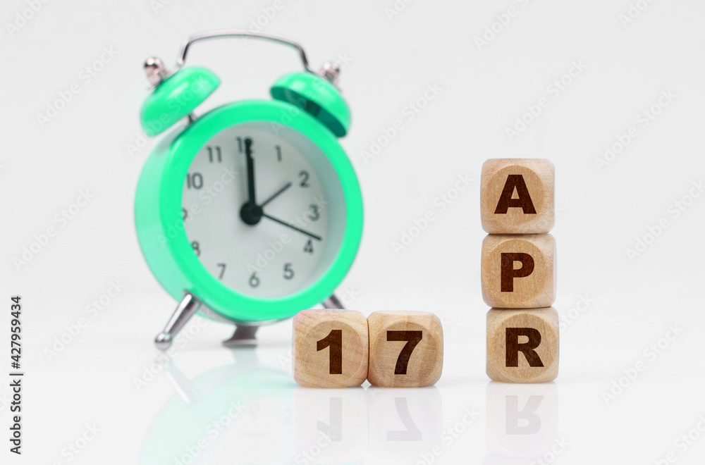 On a white background there is an alarm clock and a calendar with the inscription - April 17 On a white background there is an alarm clock and a calendar with the inscription - April 17