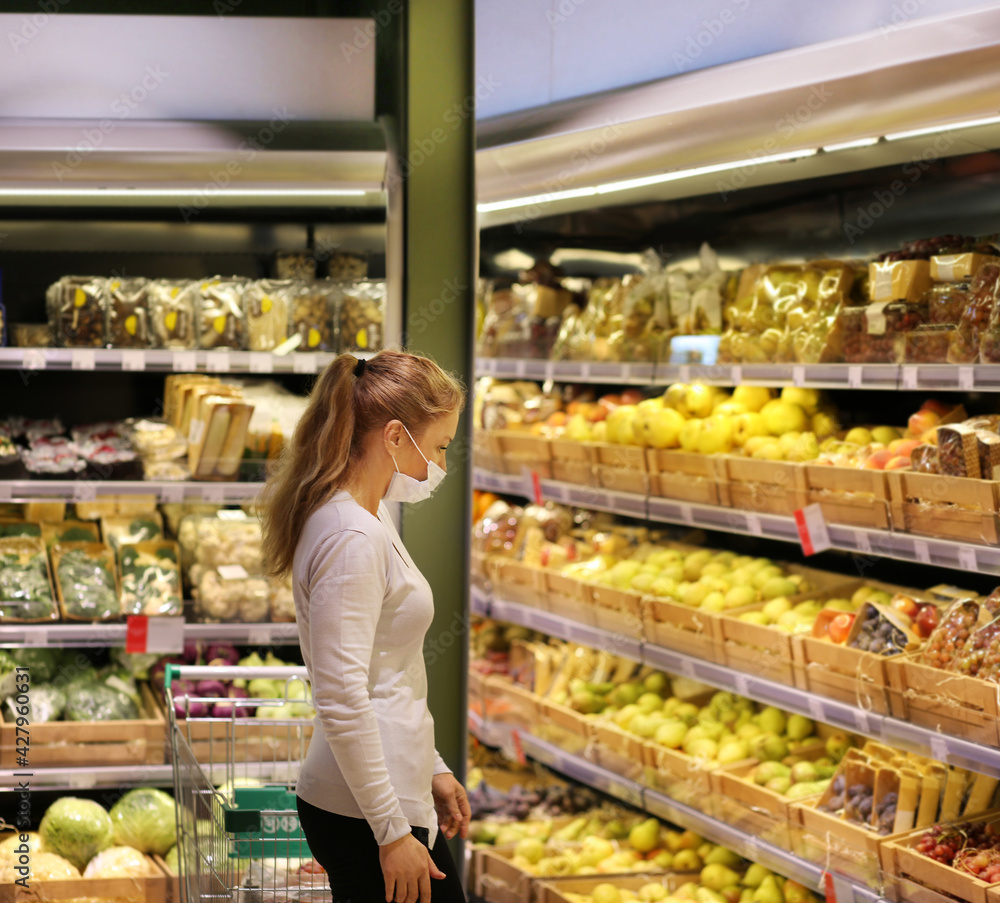 Woman buying fruits at the market.Supermarket shopping, face mask
