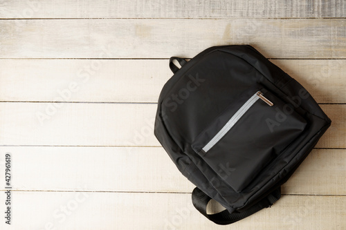 black backpack on white wooden background with copy space