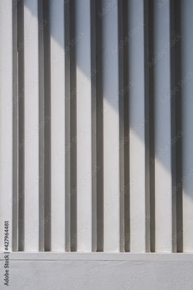 Naklejka premium Sunlight and shadow on surface of white wooden sunshade battens on cement wall in vertical frame