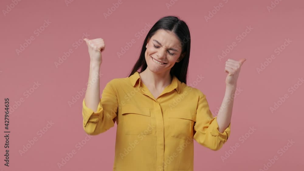 Cheerful funny brunette young latin woman 20s years old in casual yellow shirt posing isolated on pastel pink background in studio. People emotions lifestyle concept. Showing thumbs up like gesture Cheerful funny brunette young latin woman 20s years old in casual yellow shirt posing isolated on pastel pink background in studio. People emotions lifestyle concept. Showing thumbs up like gesture