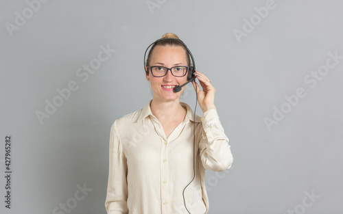 a beautiful young girl wearing an earpiece speaks affably into the microphone and smiles. She is dressed in a white silk blouse in a business-like style of clothing photo