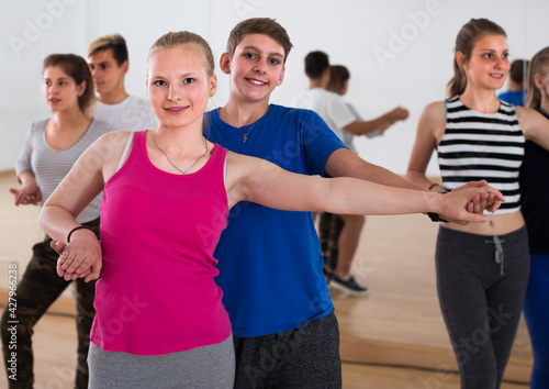 Group of admiring teenagers learning to dancing tango in dance studio