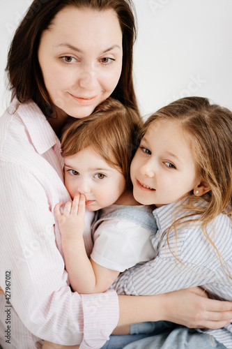 happy family sit on floor and cuddle in white photo studio.Mom and two daughters