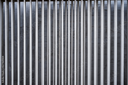 Vertical aluminium fence on concrete wall background