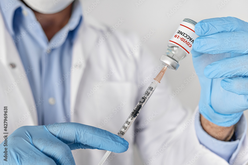 covid-19 coronavirus Vaccination concept in hand of doctor glass vaccine jar ampoule syringe . White robe and gloves covid-19 coronavirus Vaccination concept in hand of doctor glass vaccine jar ampoule syringe . White robe and gloves