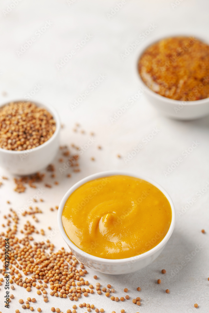 Mustard sauce in a bowl and seeds on a bright background. Mustard sauce in a bowl and seeds on a bright background.