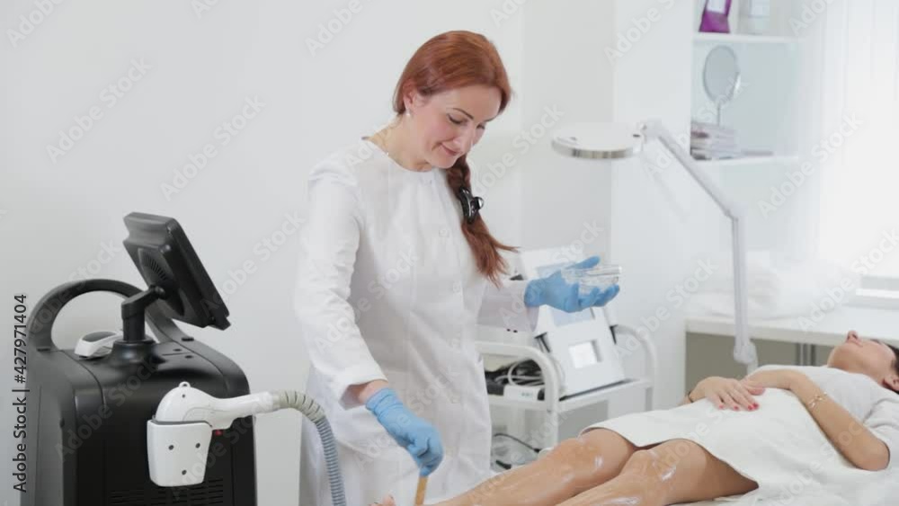 Woman beautician applies laser depilation gel to client. Woman beautician applies laser depilation gel to client.