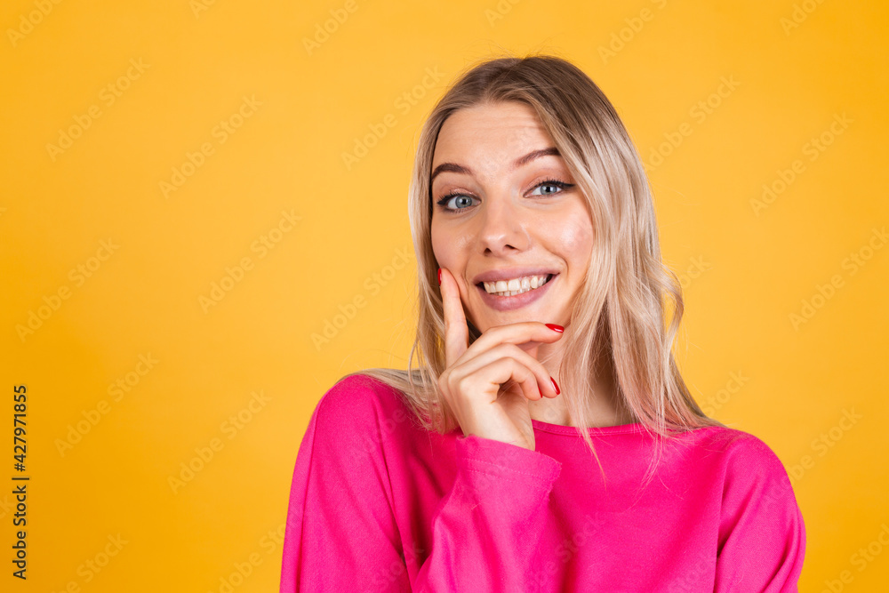 Pretty european woman in pink blouse on yellow background looks to camera thoughtfully with a sweet smile Pretty european woman in pink blouse on yellow background looks to camera thoughtfully with a sweet smile