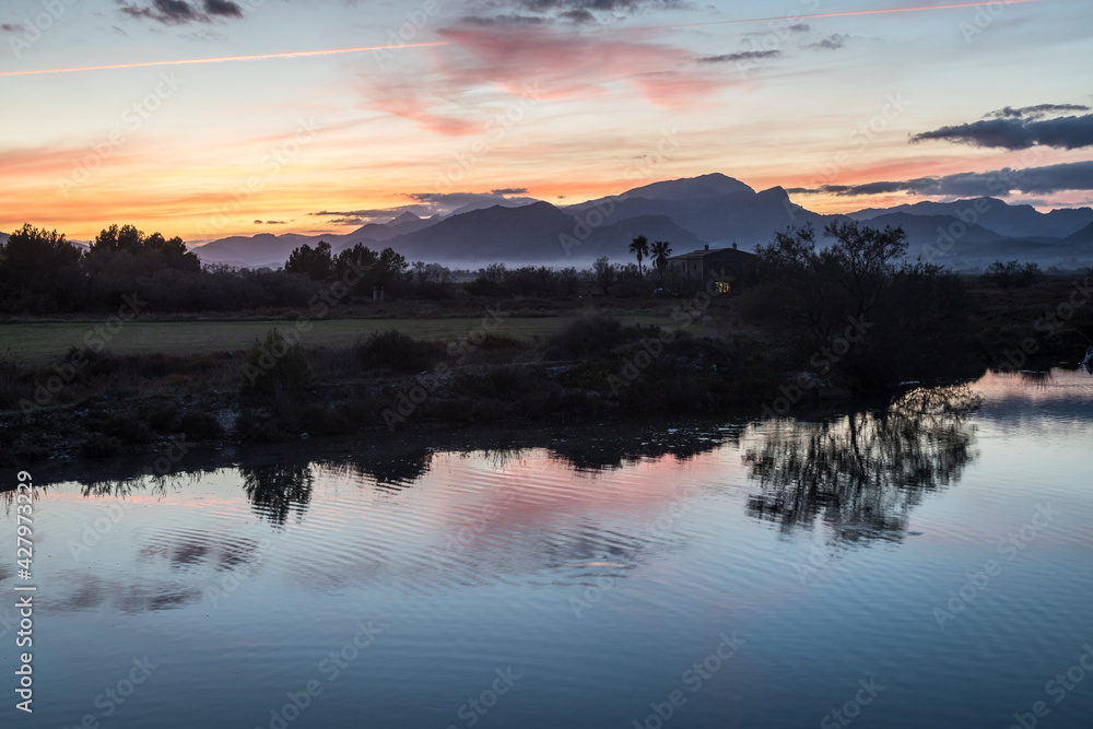Fototapeta premium Sunset at the wetlands of Albufereta in the north of Mallorca with the mountain range Serra de Tramuntana in the background.