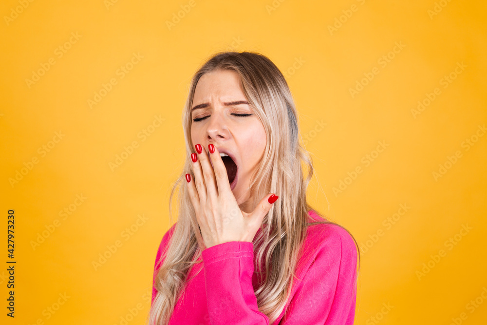 Pretty european woman in pink blouse on yellow background bored yawning tired covering mouth with hand Pretty european woman in pink blouse on yellow background bored yawning tired covering mouth with hand