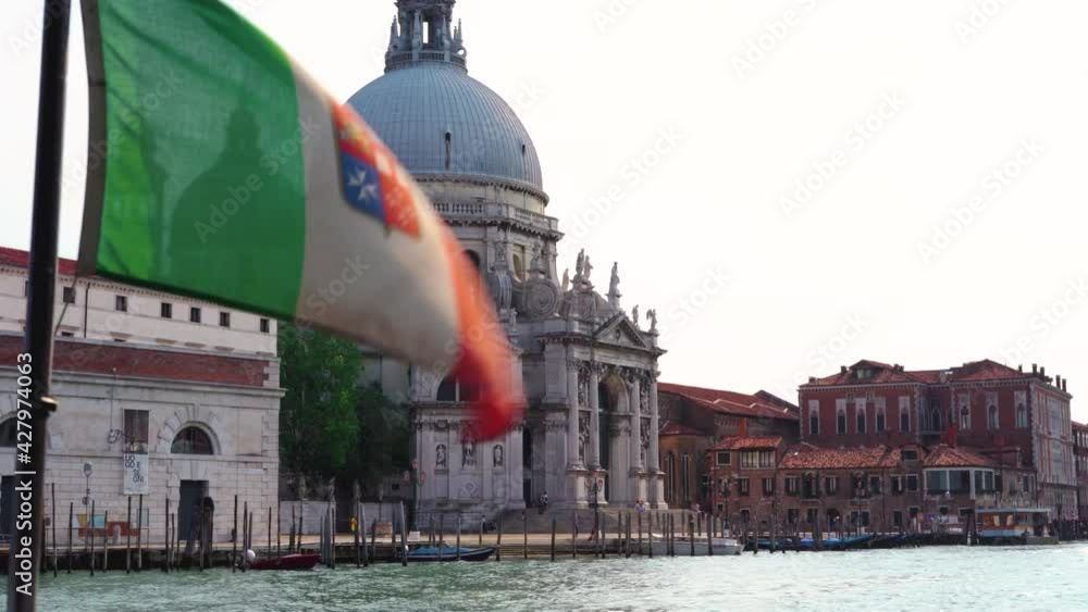 Venice - Basilica di Santa Maria della Salute with Venetian flag, from the back of a water taxi with gondolas in the foreground Venice - Basilica di Santa Maria della Salute with Venetian flag, from the back of a water taxi with gondolas in the foreground