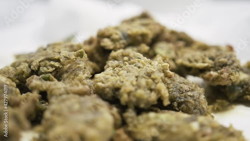 Pieces of fried Microcosmus sabatieri in luxury kitchen, orbit handheld view photo