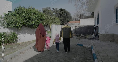 a muslim couple and their children walking