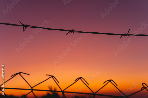 Barbed wire on sunset sky background - shallow DOF, focus on foreground