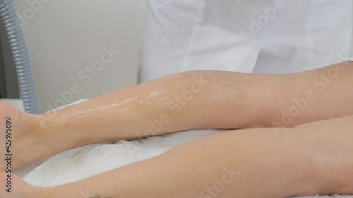 Woman beautician applies laser depilation gel to client.