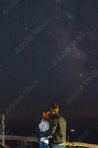 Couple traveler enjoying watched the star and milky way galaxy over the sky on top of the mountain. Night landscape with beautiful sky. Vertical photo