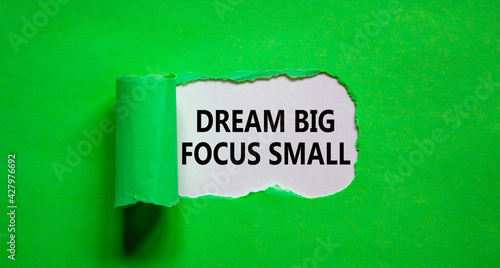 Dream big focus small symbol. Concept words 'dream big focus small' appearing behind torn green paper. Business, motivational and dream big focus small concept.