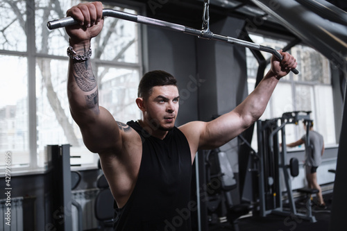 Focused bodybuilder exercising on lat pulldown gym machine